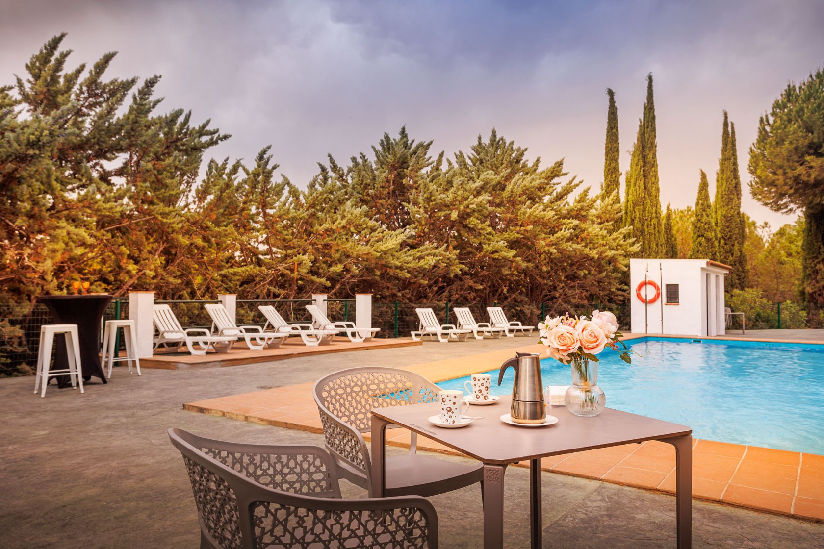 Mesa preparada junto a la piscina al atardecer