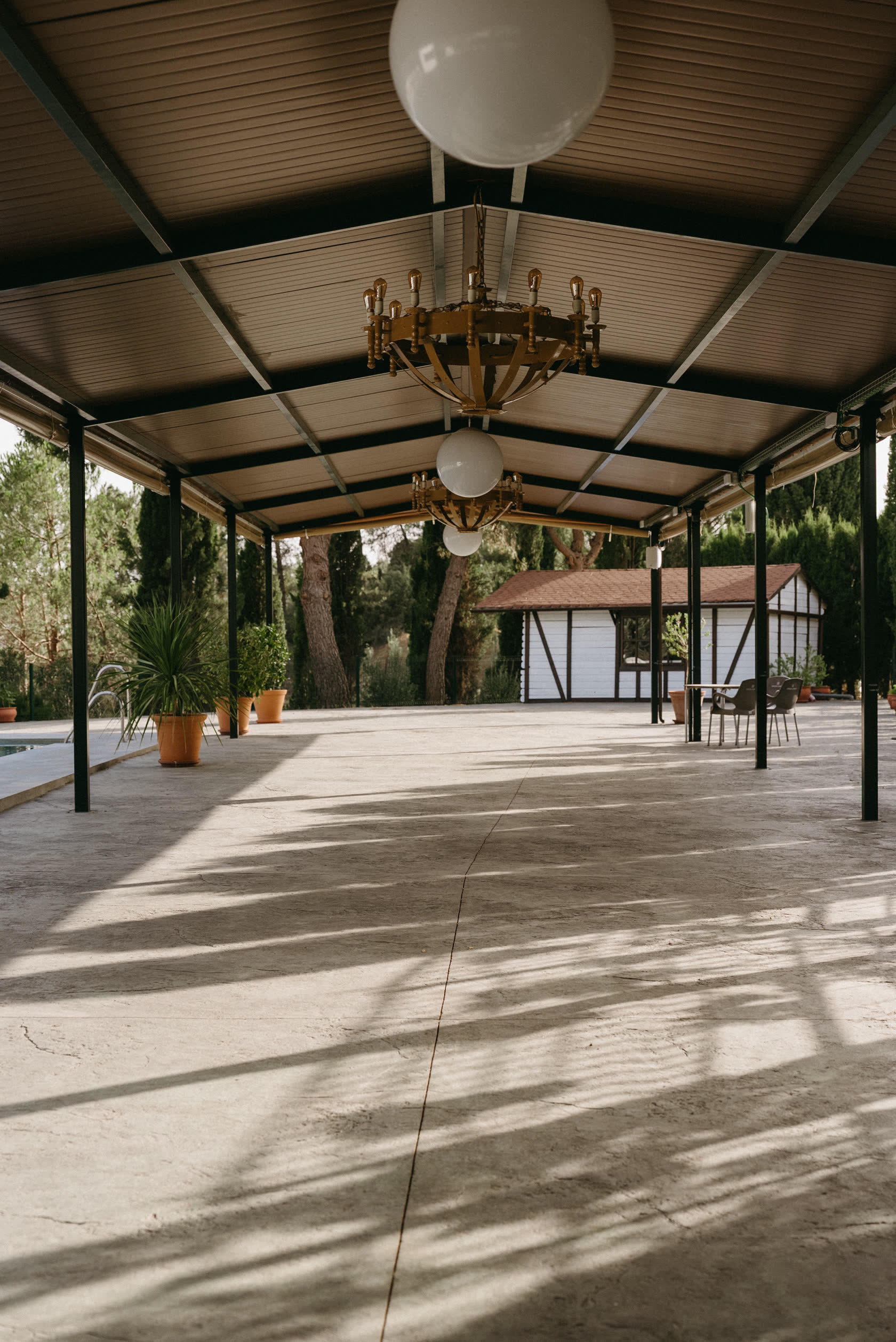 Interior de la zona cubierta para eventos, con techo de madera y ventanales